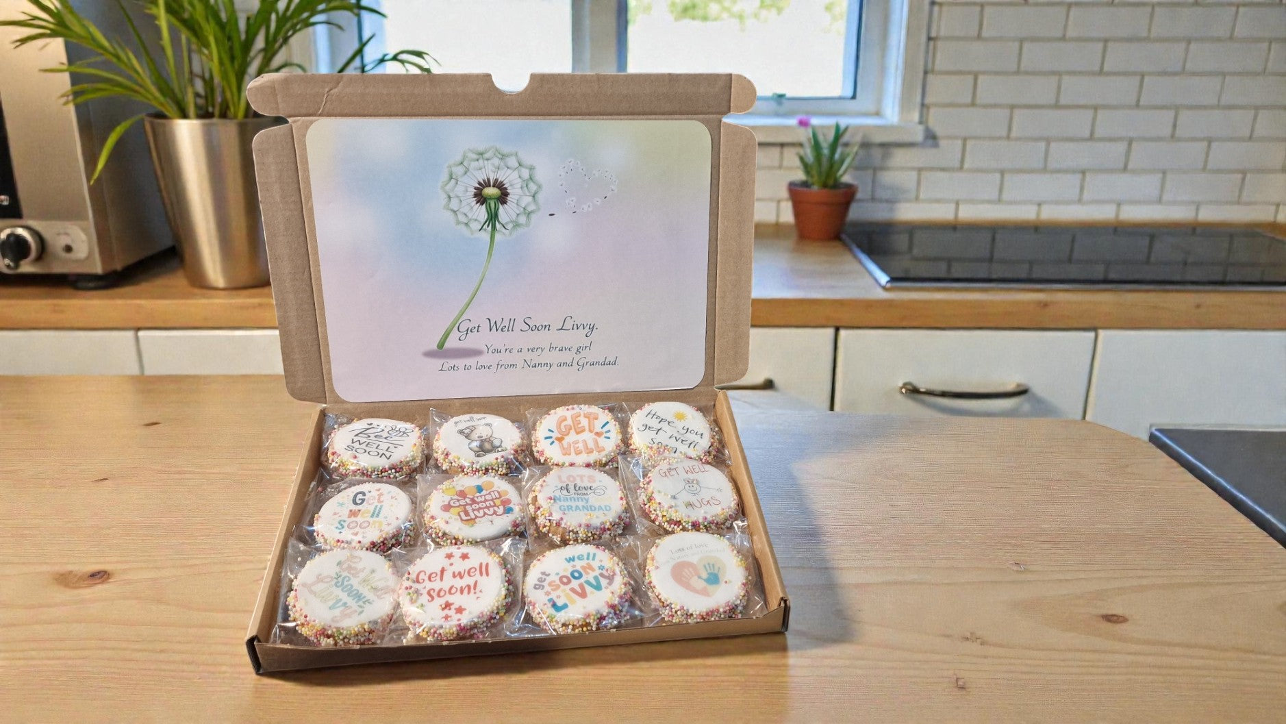 Box of cupcakes with personalized designs on a kitchen counter