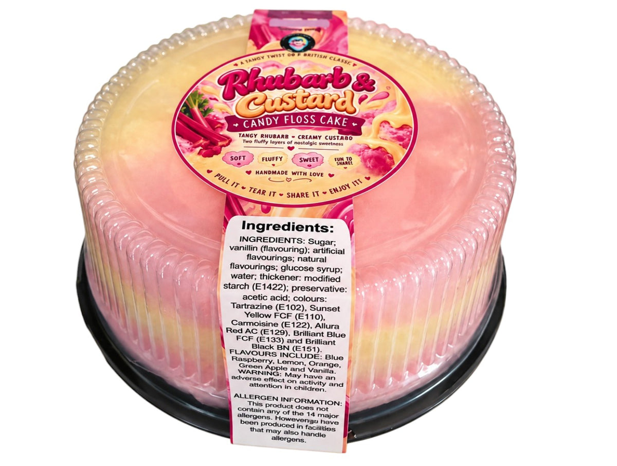A packaged two-tone candy floss cake in a clear plastic tub with a decorative scalloped rim. The top half is creamy yellow, and the bottom half is light pink, with a large pink and yellow label reading 'Rhubarbs & Custard Candy Floss Cake' and a white ingredients tag on the front.