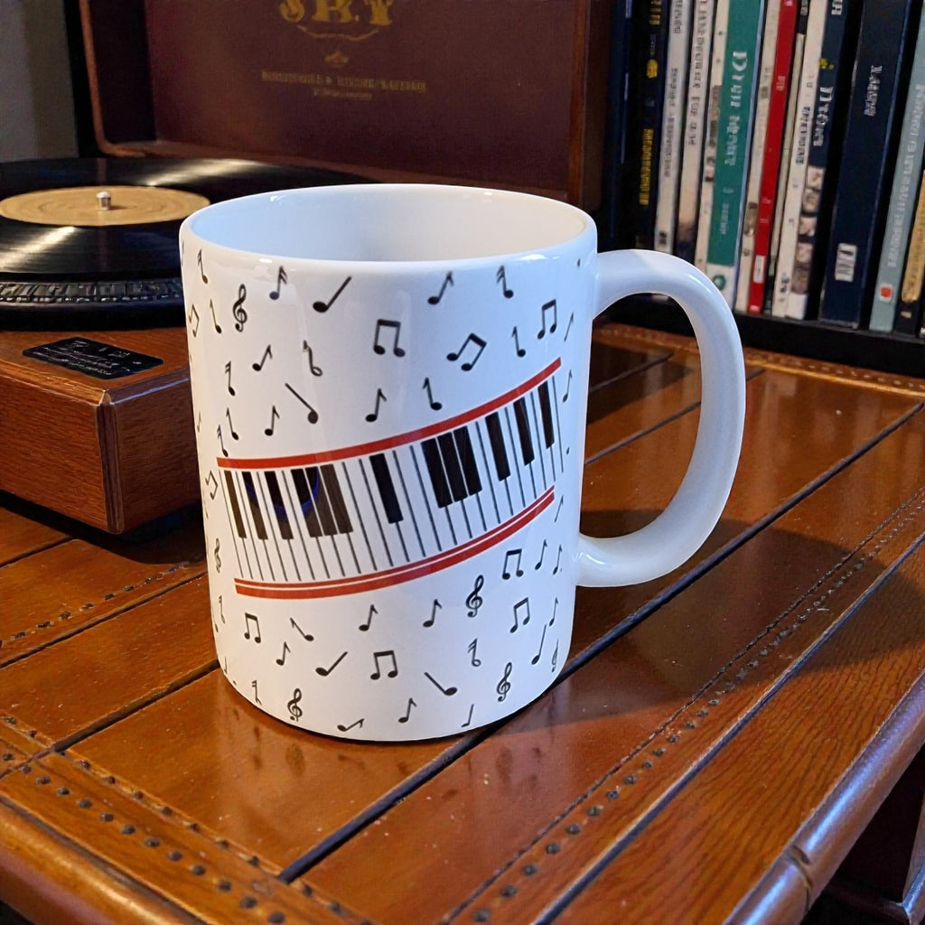 Mug with musical notes and piano keys design on a wooden surface with books in the background