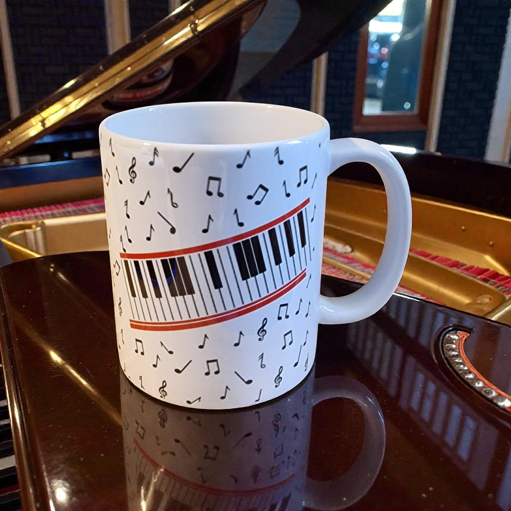 White mug with musical notes and piano keys design on a reflective surface