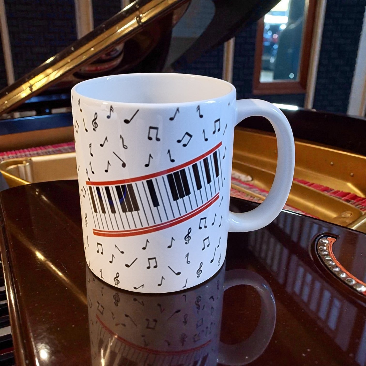White mug with musical notes and piano keys design on a reflective surface