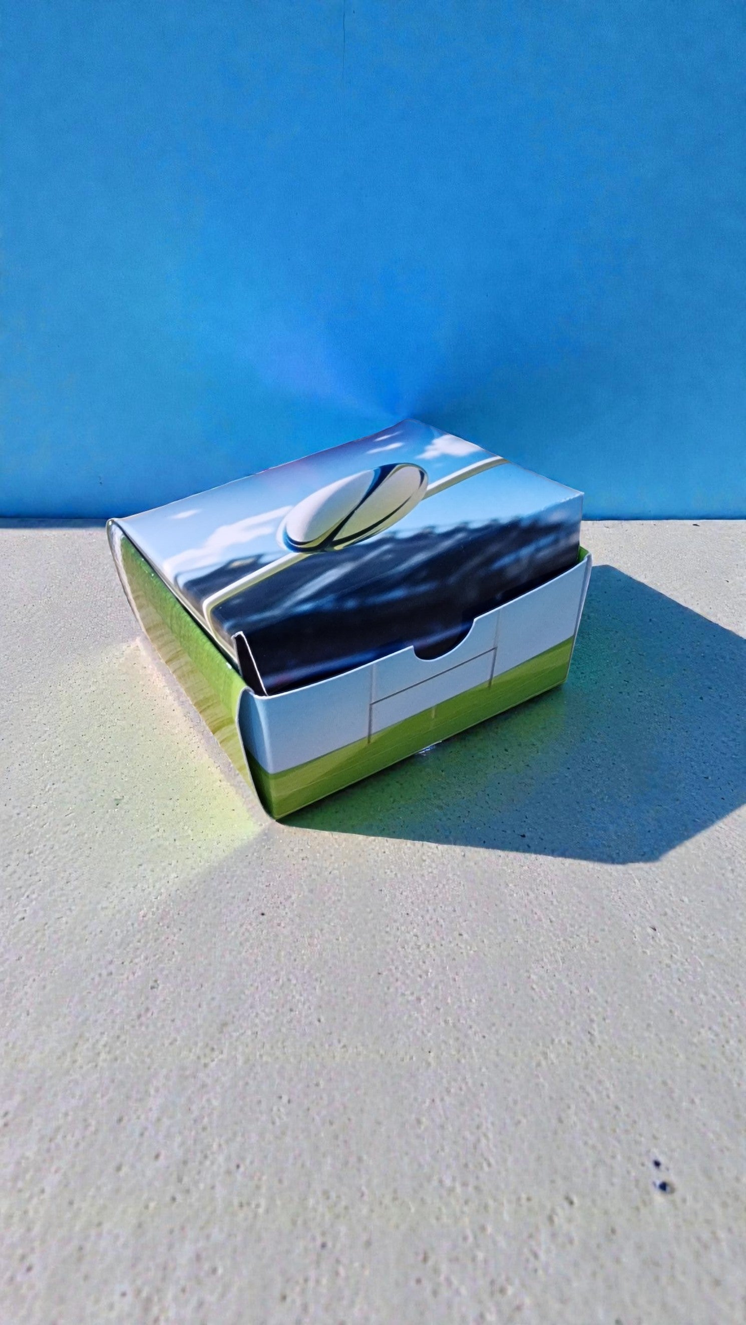 Chrome rectangular object on a textured surface with a blue background