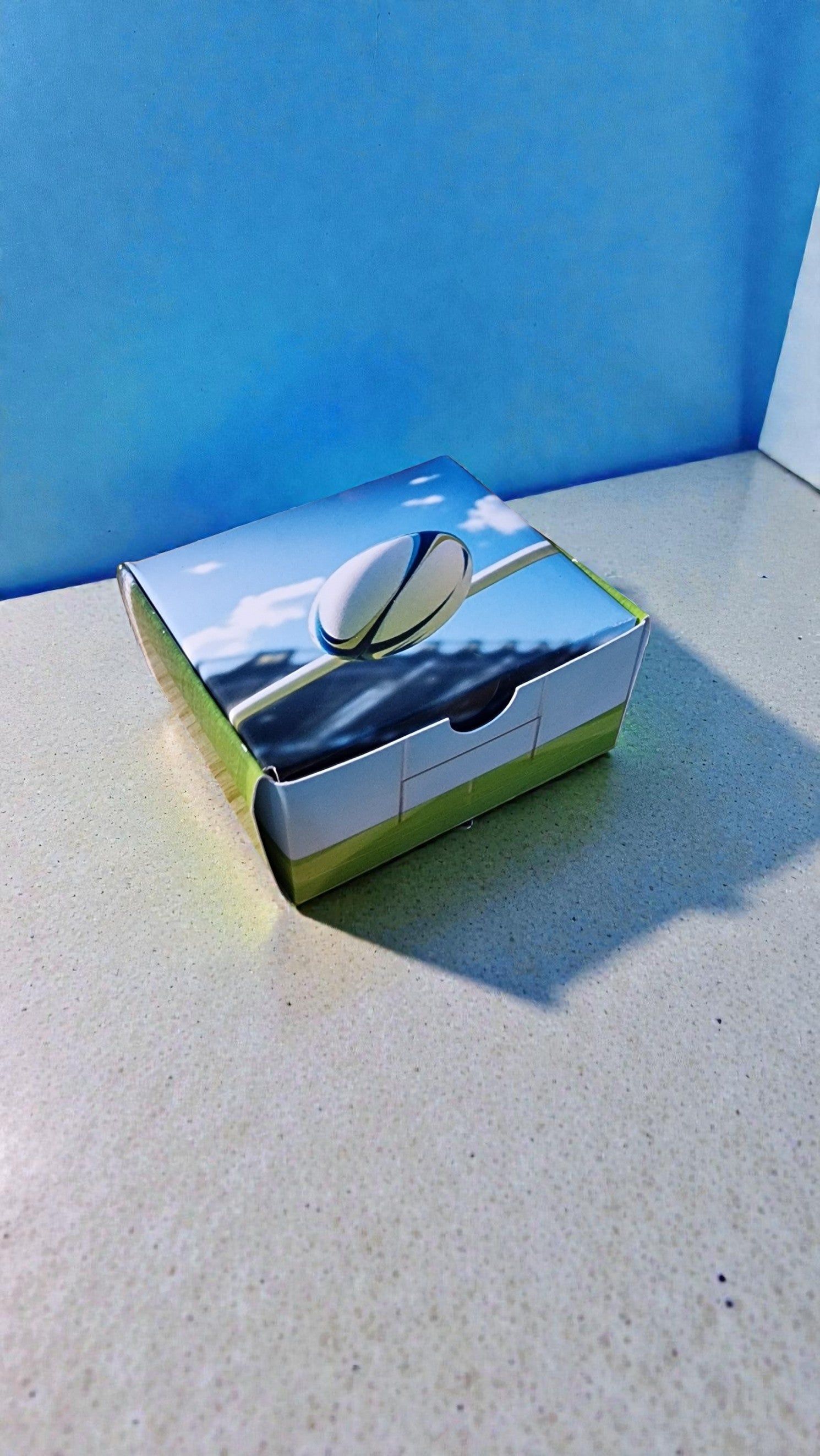 Small box with a reflective surface showing a blue sky and white clouds.