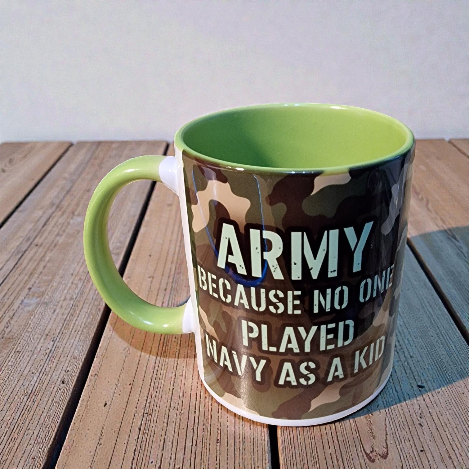 Camouflage-patterned mug with text on a wooden surface