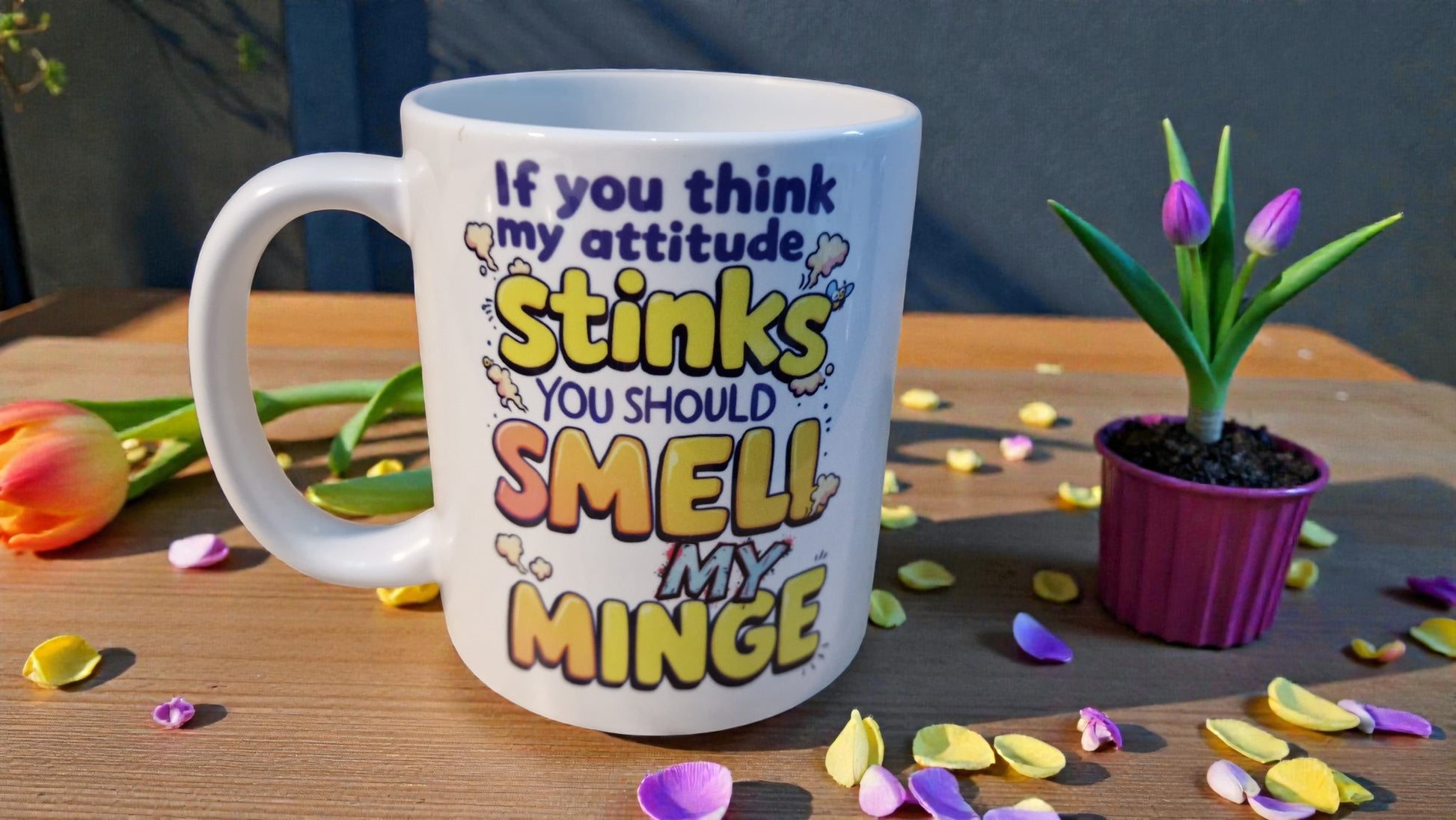 Mug with humorous text on a table with flowers and confetti