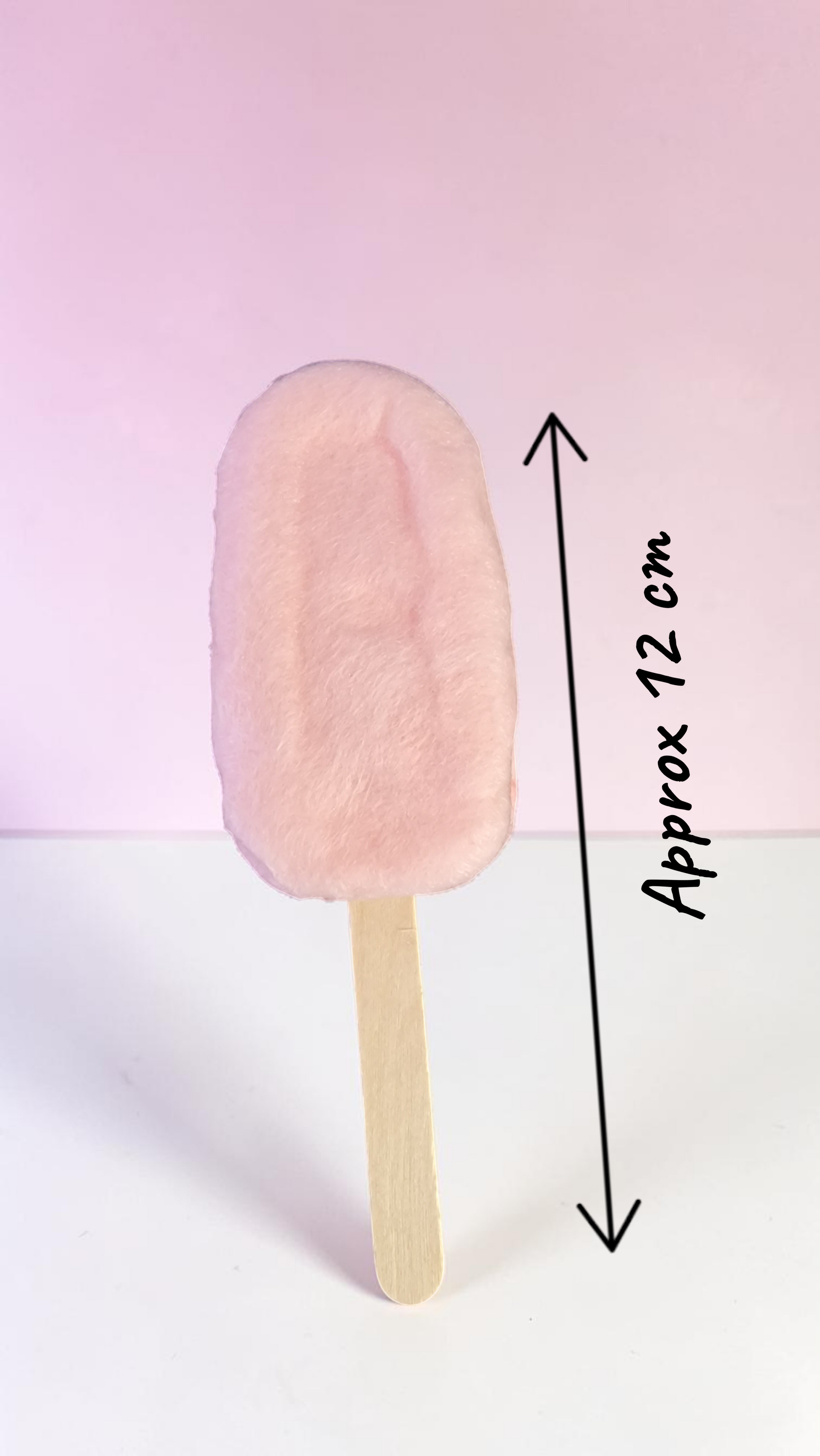 Pink ice cream bar on a stick with a measurement label on a pink background