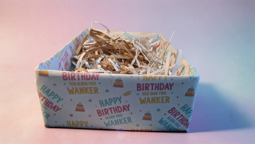 Box with 'Happy Birthday Wanker' text on a pastel gradient background