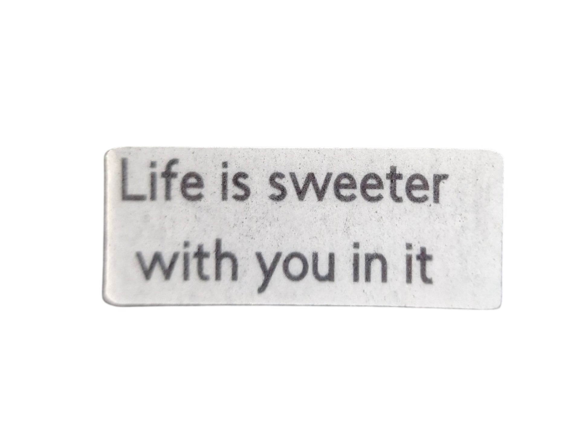 Rectangular metal sign with engraved text 'Life is sweeter with you in it' on a white background