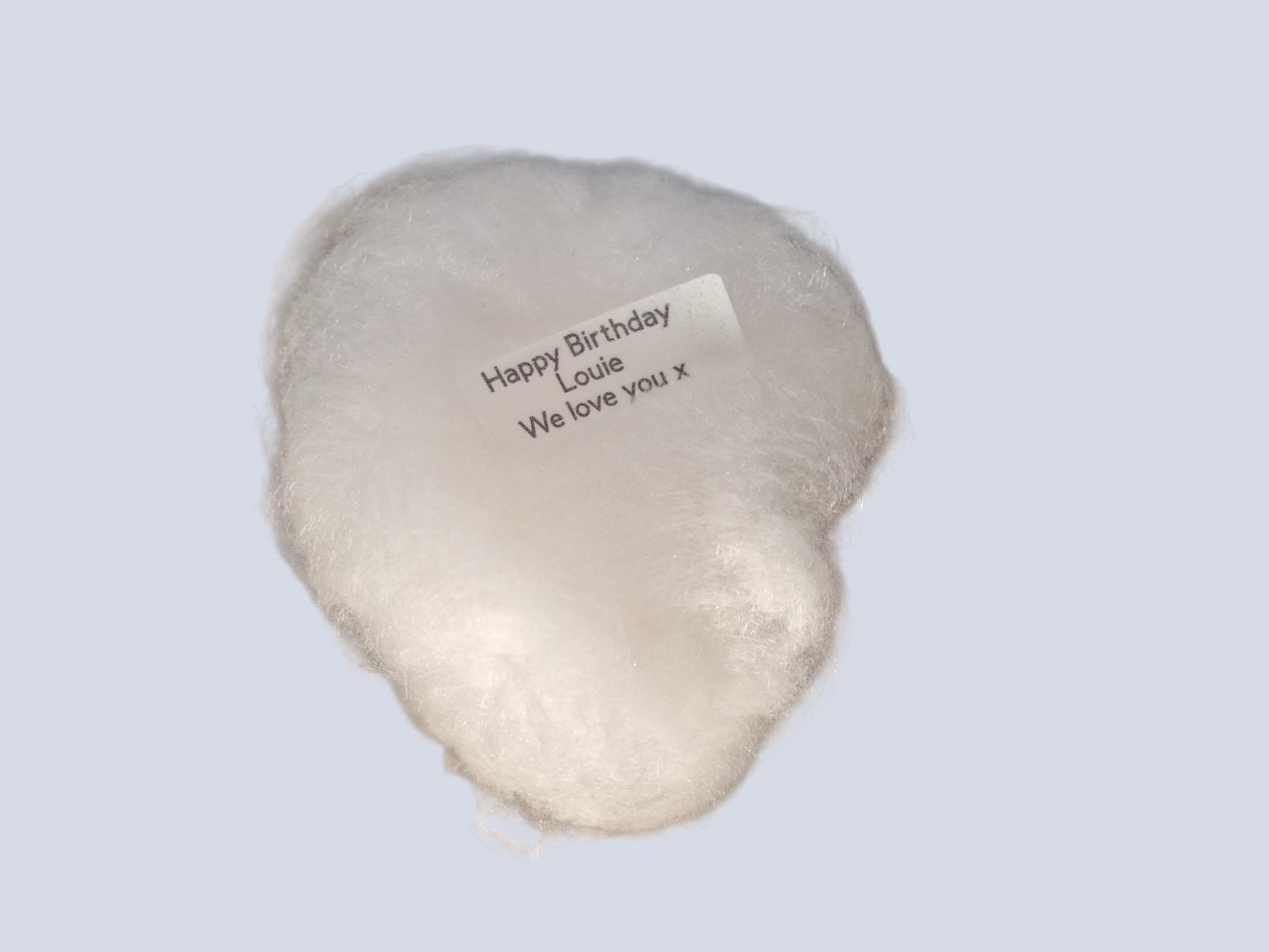 White plush heart with a message on a light gray background