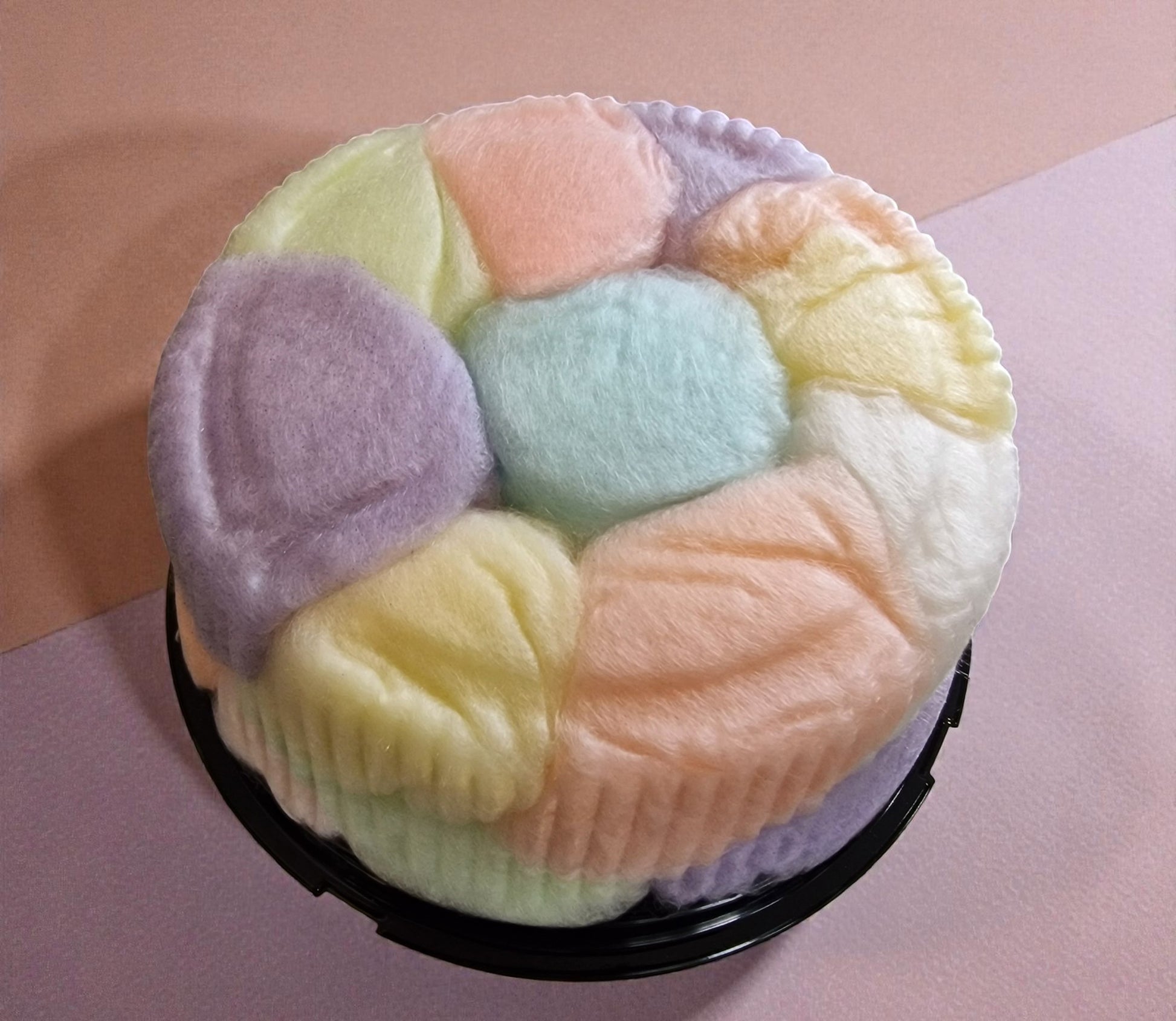 Pastel-colored marshmallow treats in a black container on a pink background