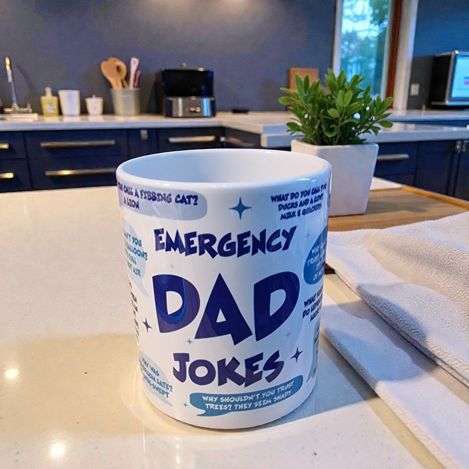 Mug with 'Emergency Dad Jokes' text on a kitchen counter