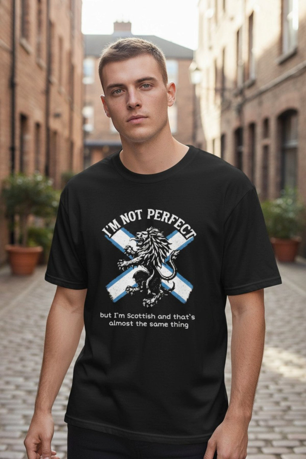 Man wearing a black t-shirt with Scottish design and text on a street.