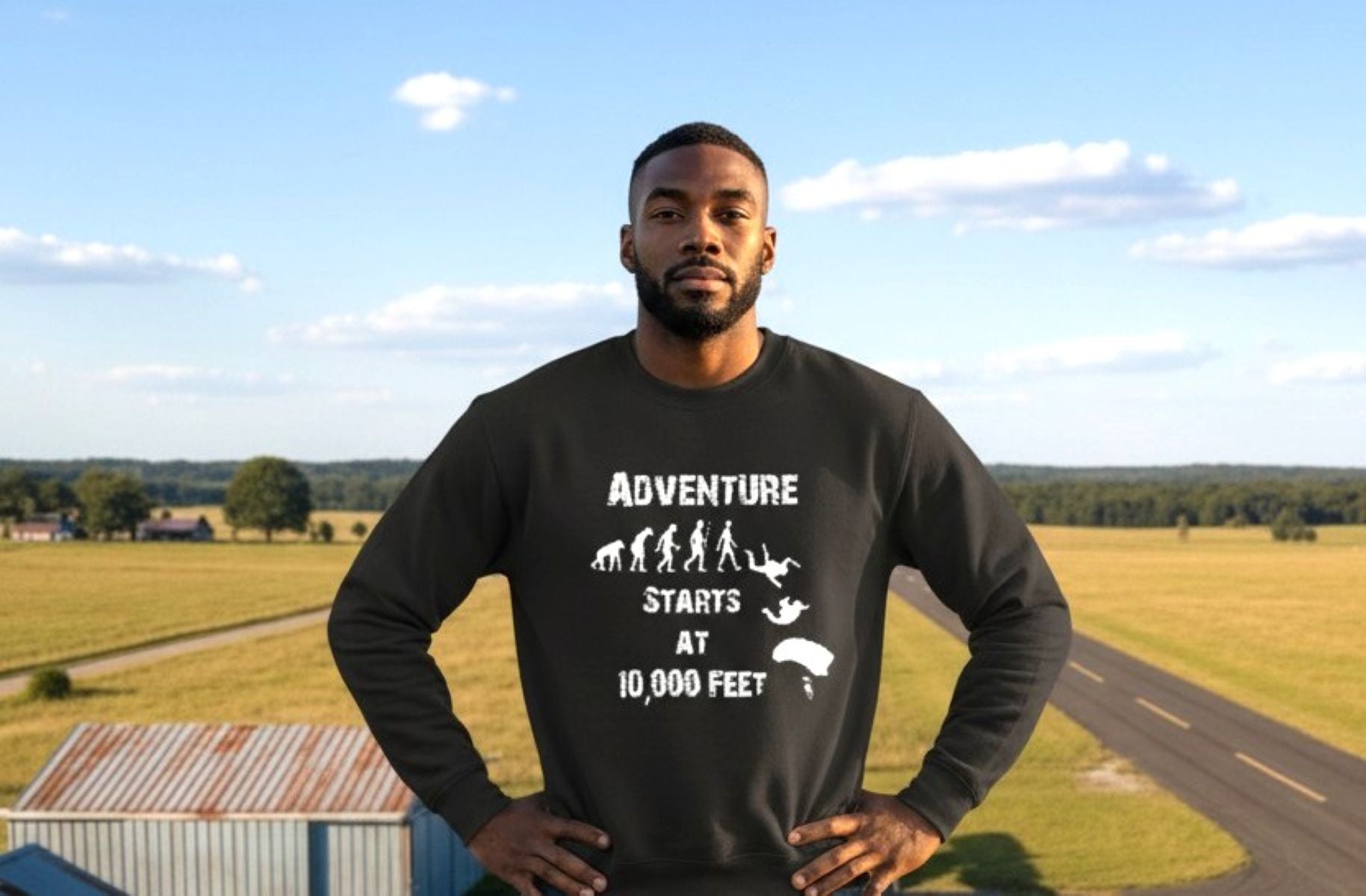 Man wearing a black sweatshirt with 'Adventure Starts at 10,000 Feet' text and graphic, standing outdoors.
