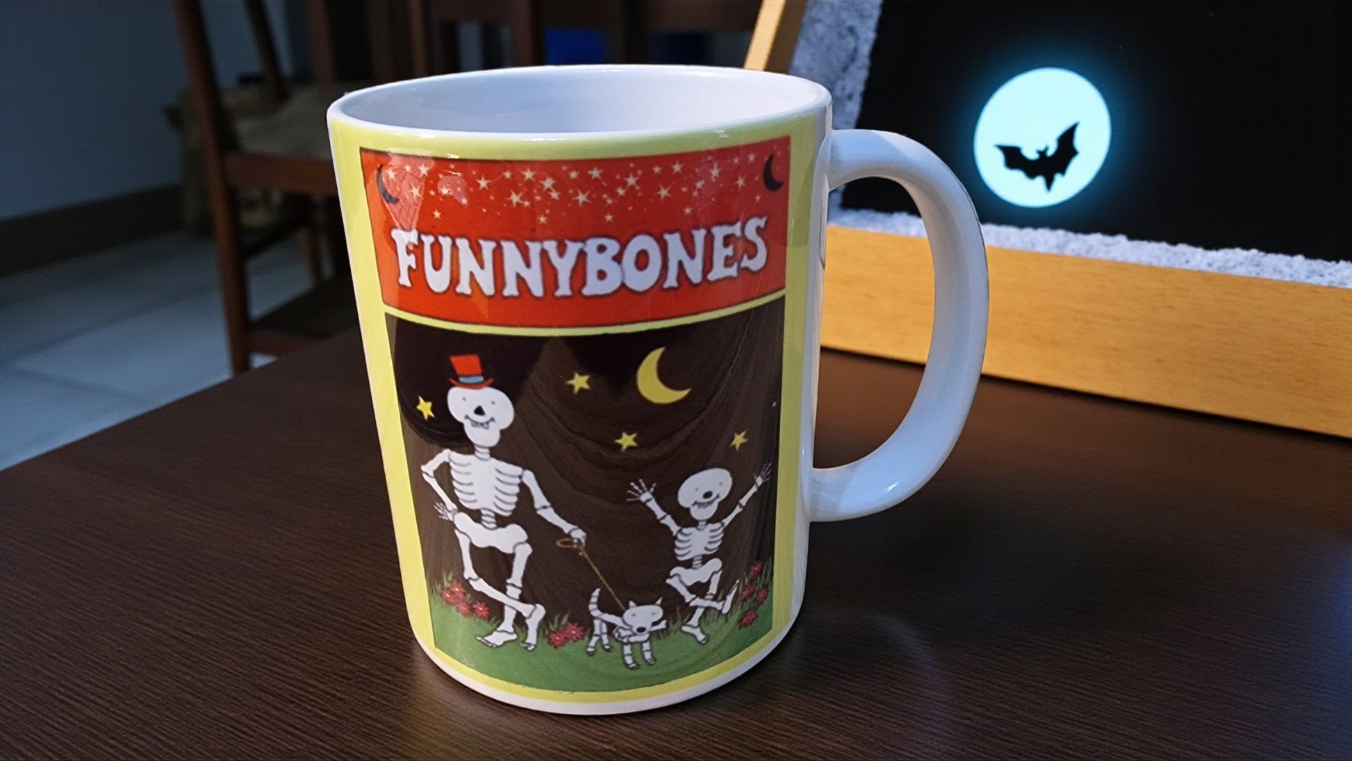 Mug with 'Funnybones' design featuring skeletons on a wooden surface.
