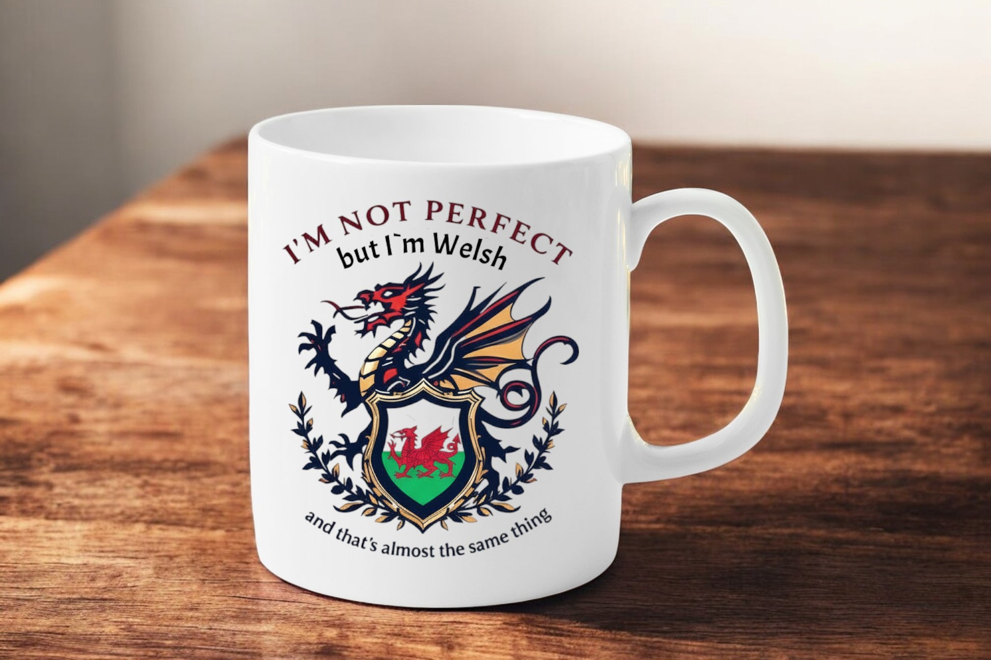 White mug with Welsh dragon design and text on a wooden surface