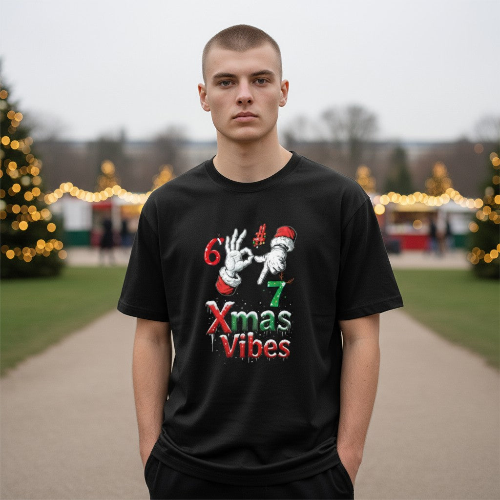 Person wearing a black t-shirt with Christmas-themed design in an outdoor setting with trees and lights.