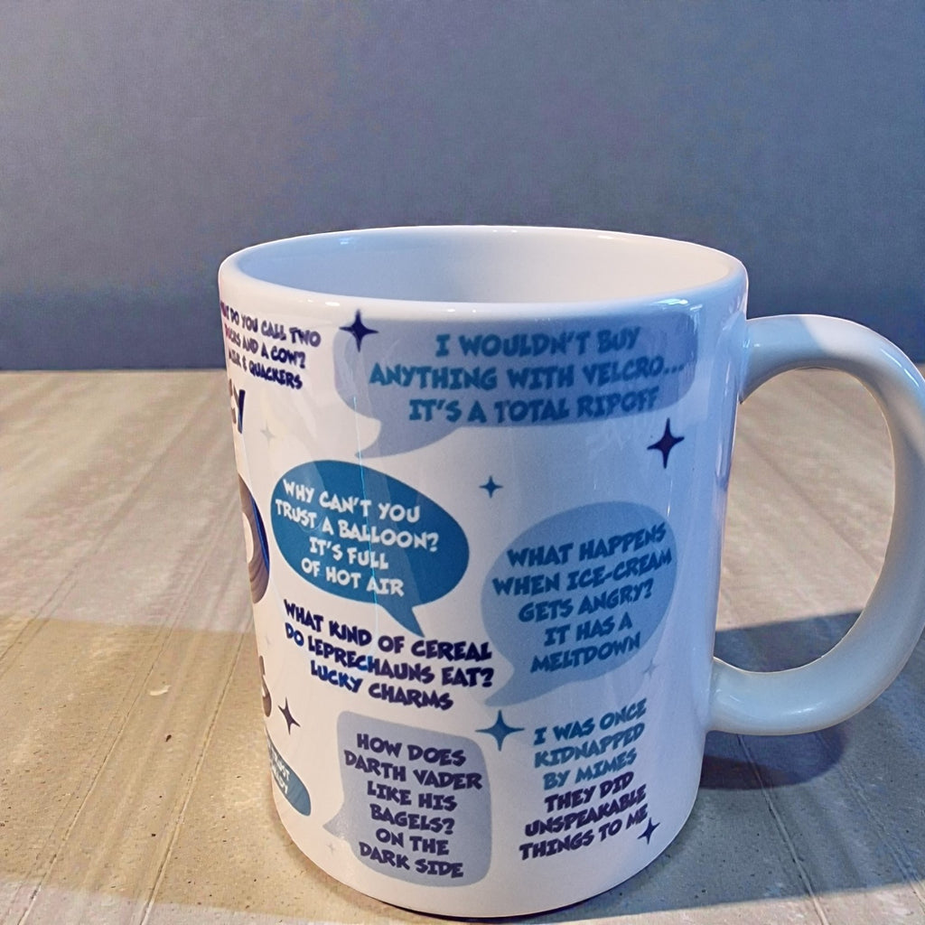 White mug with blue text and graphics on a wooden surface